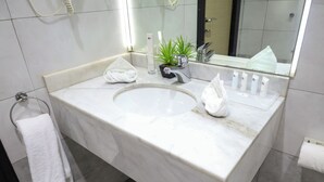 A modern bathroom with a marble sink, a small potted plant, a towel, and toiletries. - Lahdat Hotel Al Balad (Jeddah)