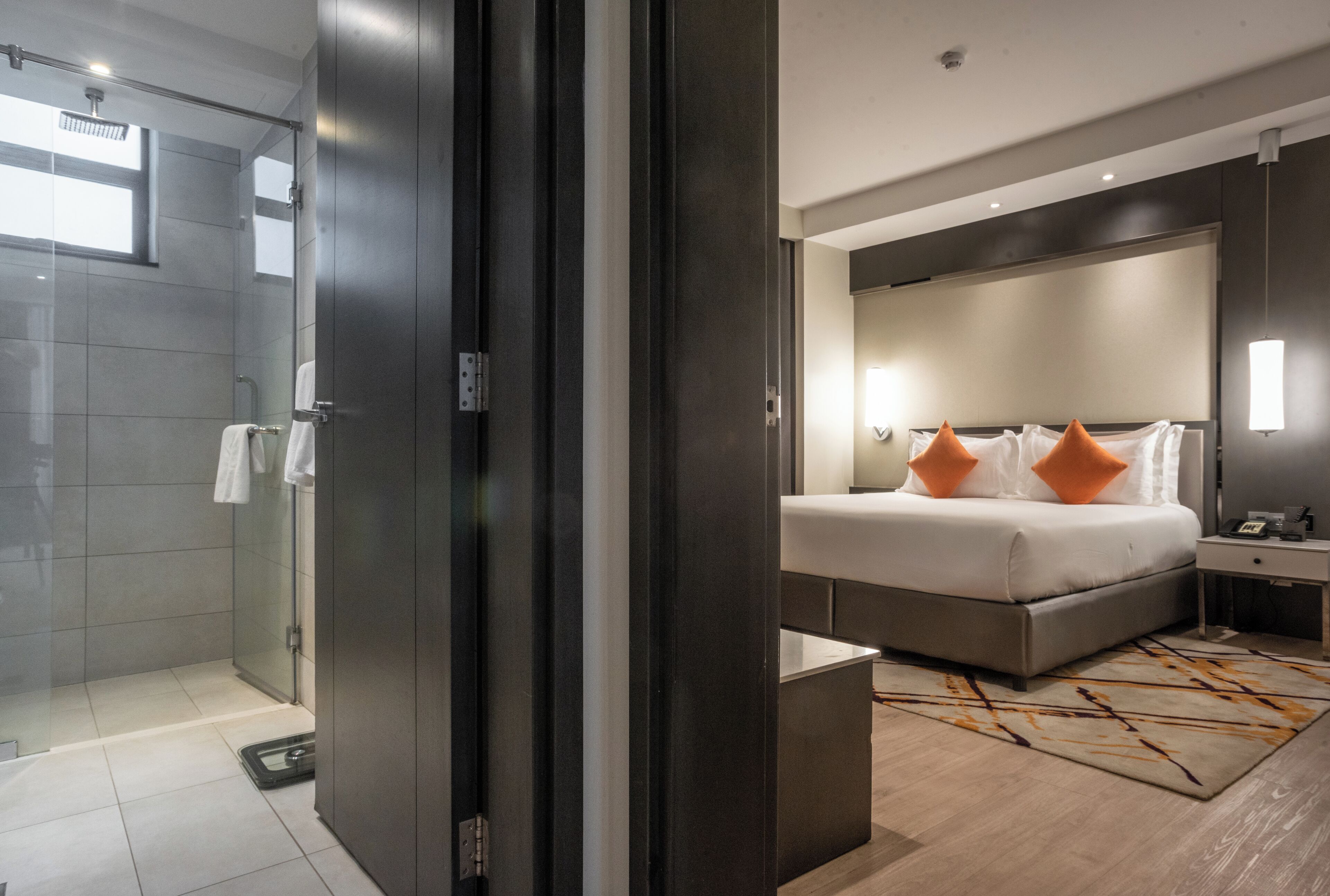 Een moderne hotelkamer met een groot bed, een nachtkastje en een douchecabine van glas.