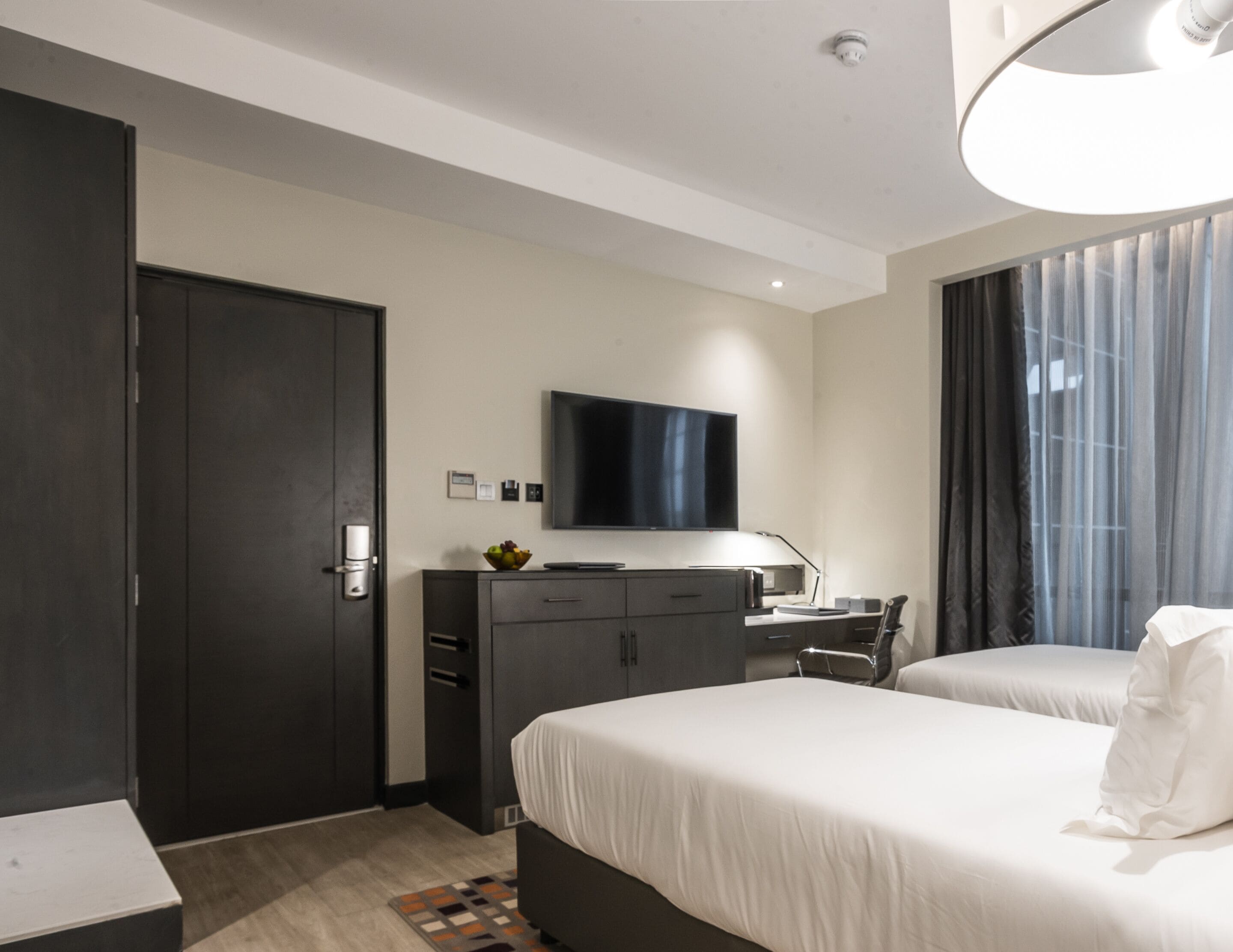 Une chambre d’hôtel moderne dotée d’un grand lit, d’un bureau avec un ordinateur, d’une télévision à écran plat et d’une armoire.