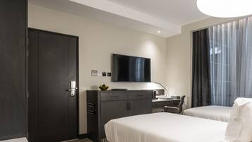 Une chambre d’hôtel moderne dotée d’un grand lit, d’un bureau avec un ordinateur, d’une télévision à écran plat et d’une armoire.