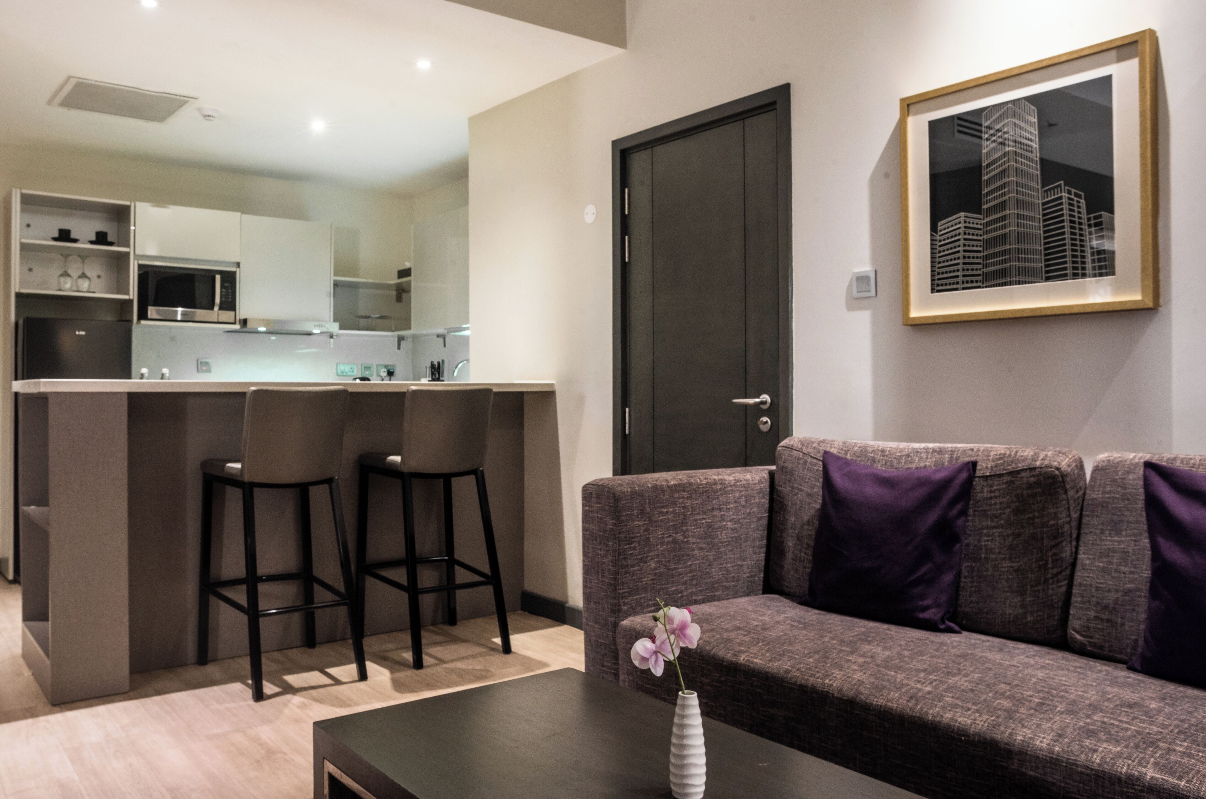 A modern living room with a sofa, a coffee table, and a bar area with stools.