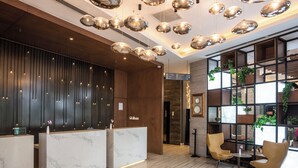A modern reception area with marble reception desks, a wooden panel wall, and a seating area with yellow chairs and a small table. - Best Western Premier Westlands (Nairobi)