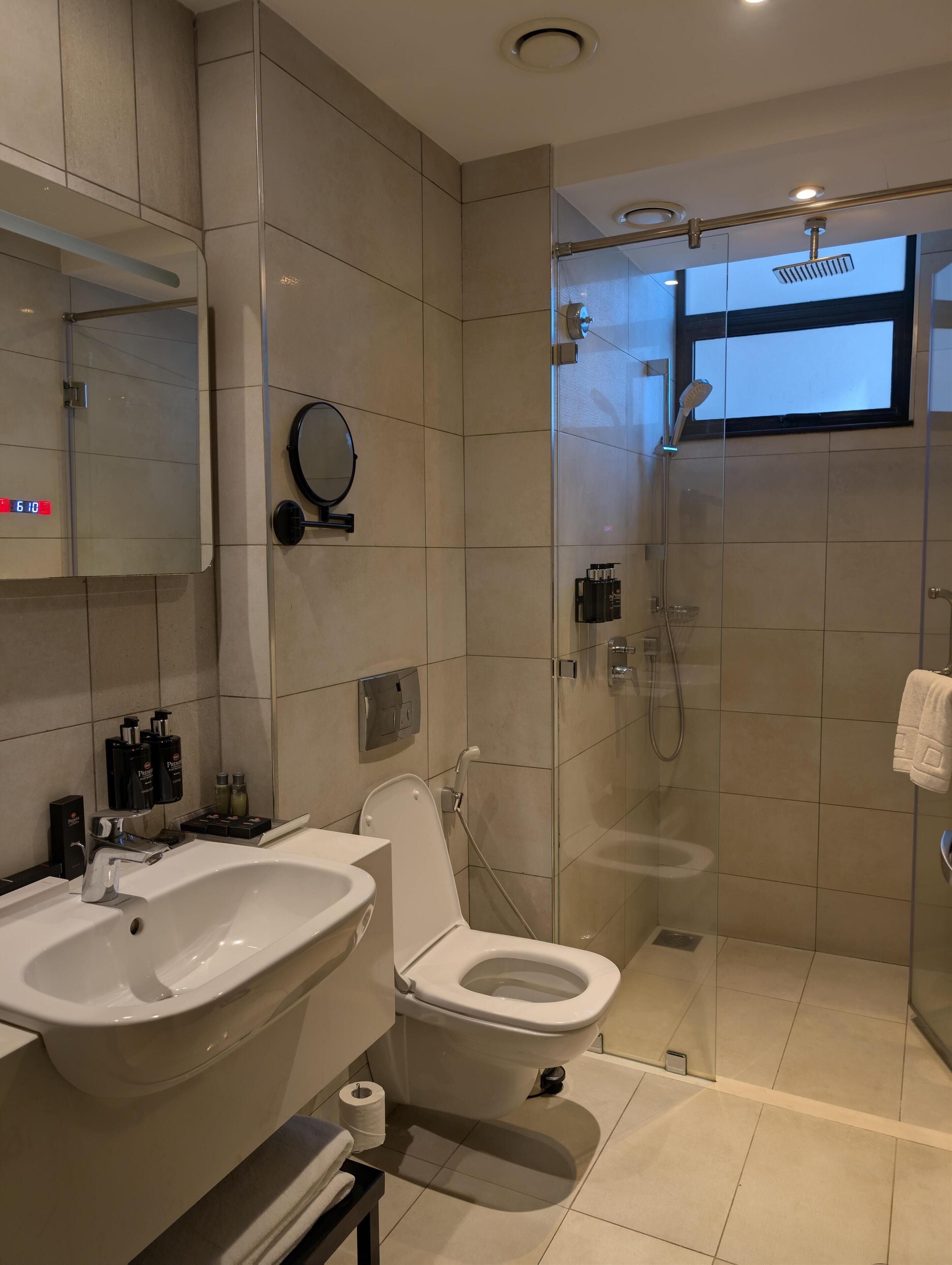 A modern bathroom with a glass-enclosed shower, a white sink, and a toilet.