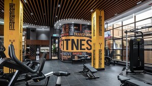 Una palestra con diverse attrezzature per l'allenamento, grafiche motivazionali a parete e un'ampia finestra che garantisce luce naturale.