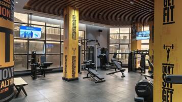 Un gimnasio con equipo de ejercicio, carteles motivacionales y un ventanal amplio.
