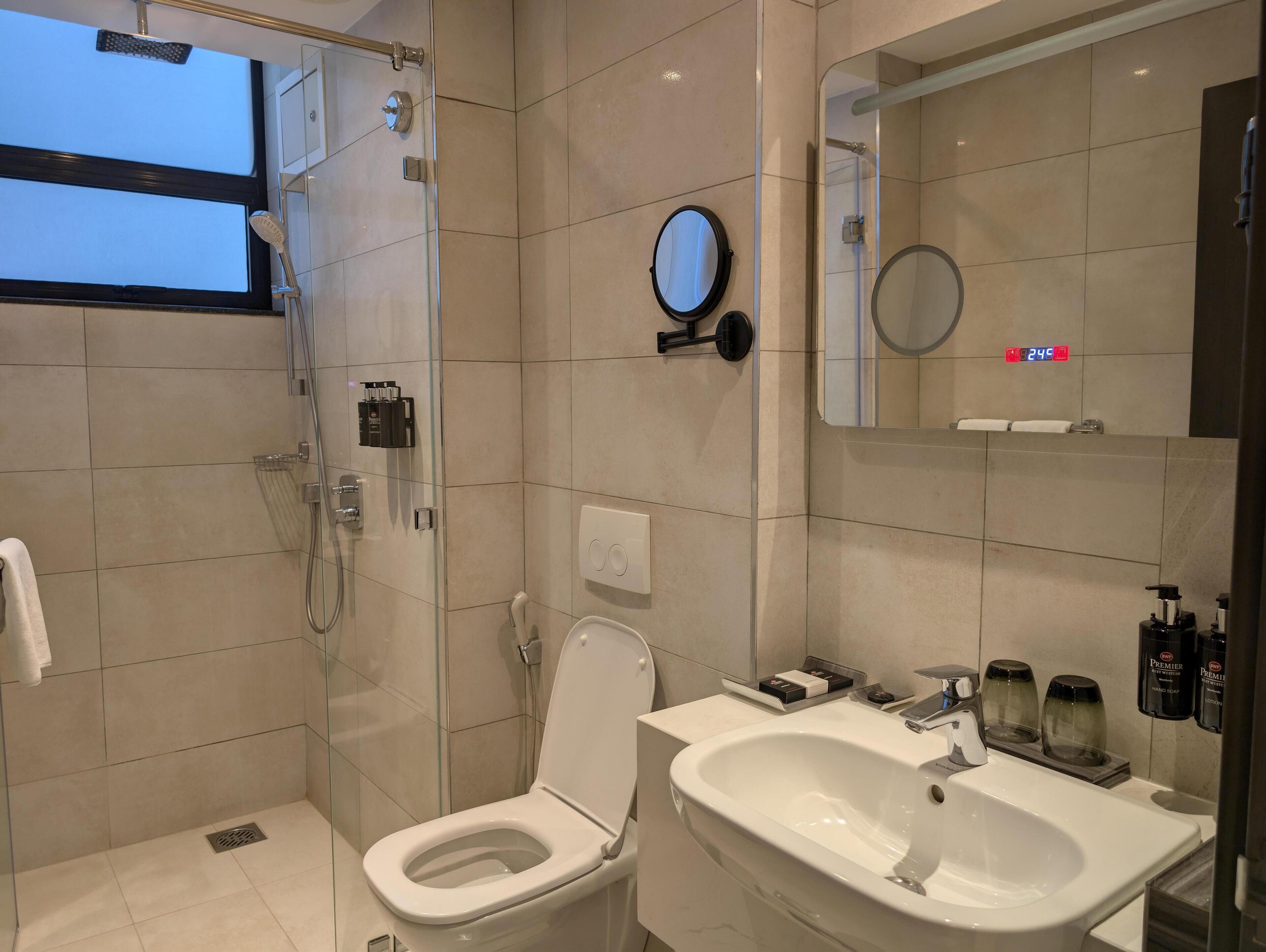 A modern bathroom with a glass-enclosed shower, a toilet, and a sink.