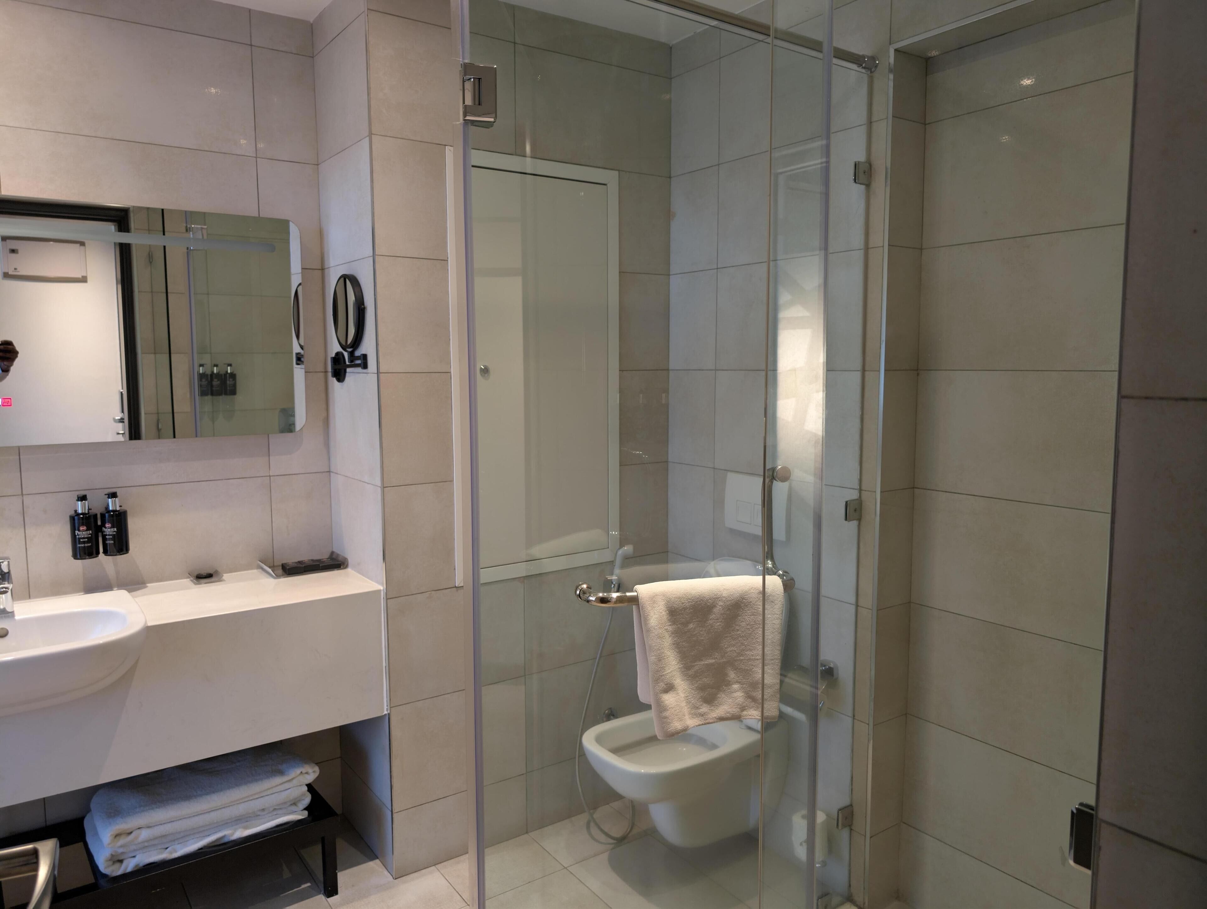 A modern bathroom with a glass-enclosed shower, a white sink, and a mirror above it.