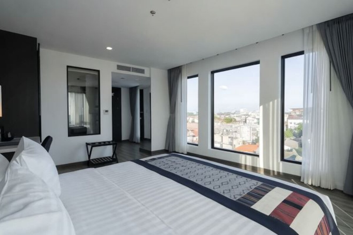 Una habitación de hotel moderna con una cama grande, un escritorio y vistas a la ciudad.