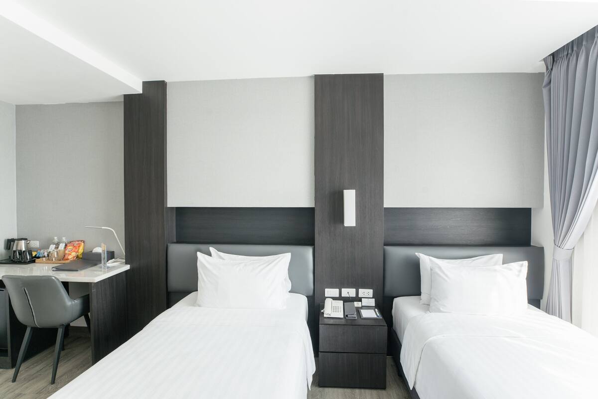 A hotel room with two beds, a desk, and a chair.