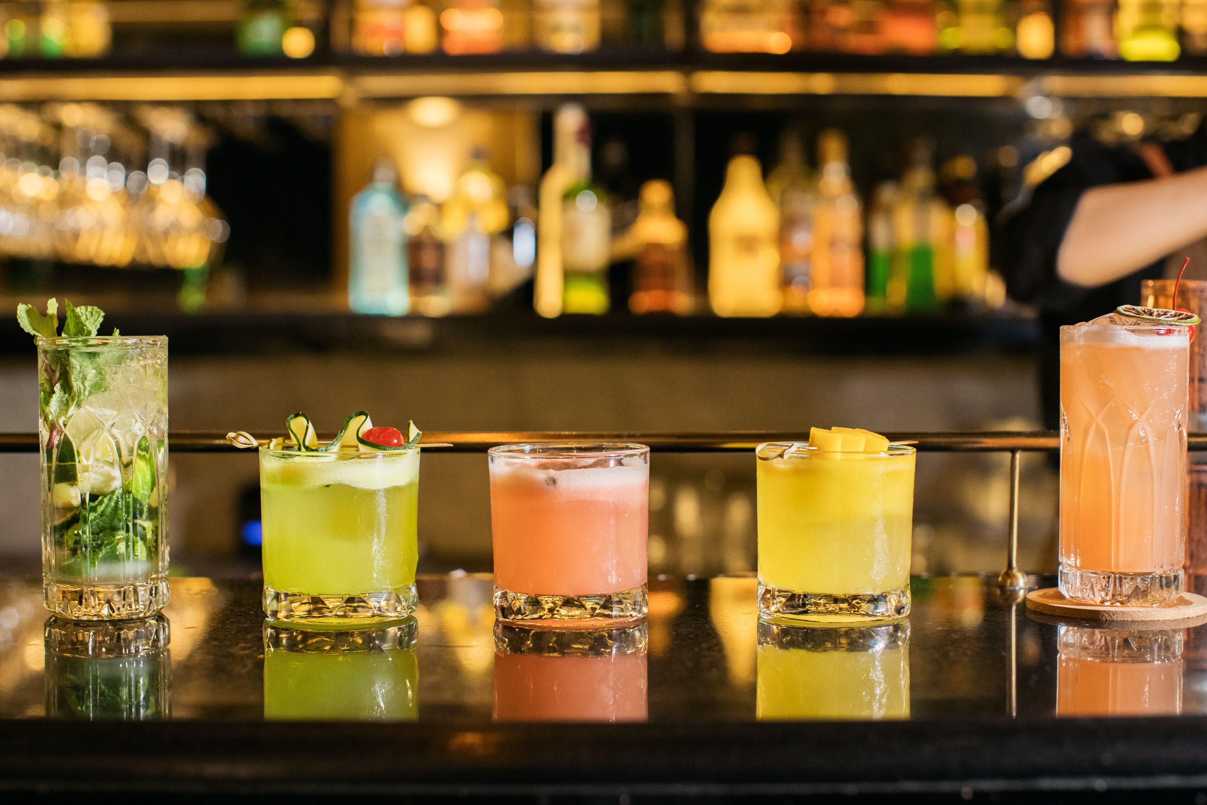 Eine Bar mit fünf verschiedenen Cocktails auf der Theke.