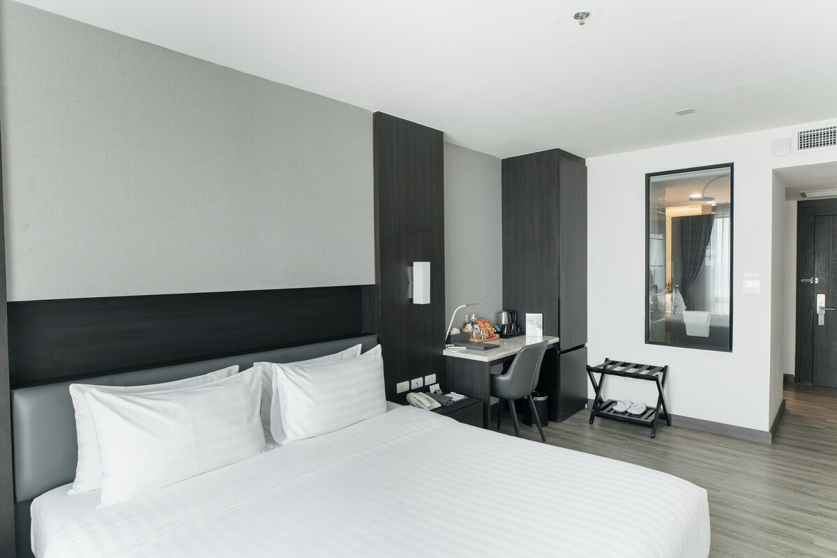 Una habitación de hotel moderna con una cama grande, un escritorio y una silla.