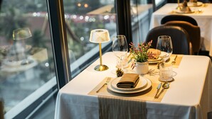 A neatly set dining table with a view of the city through large windows.