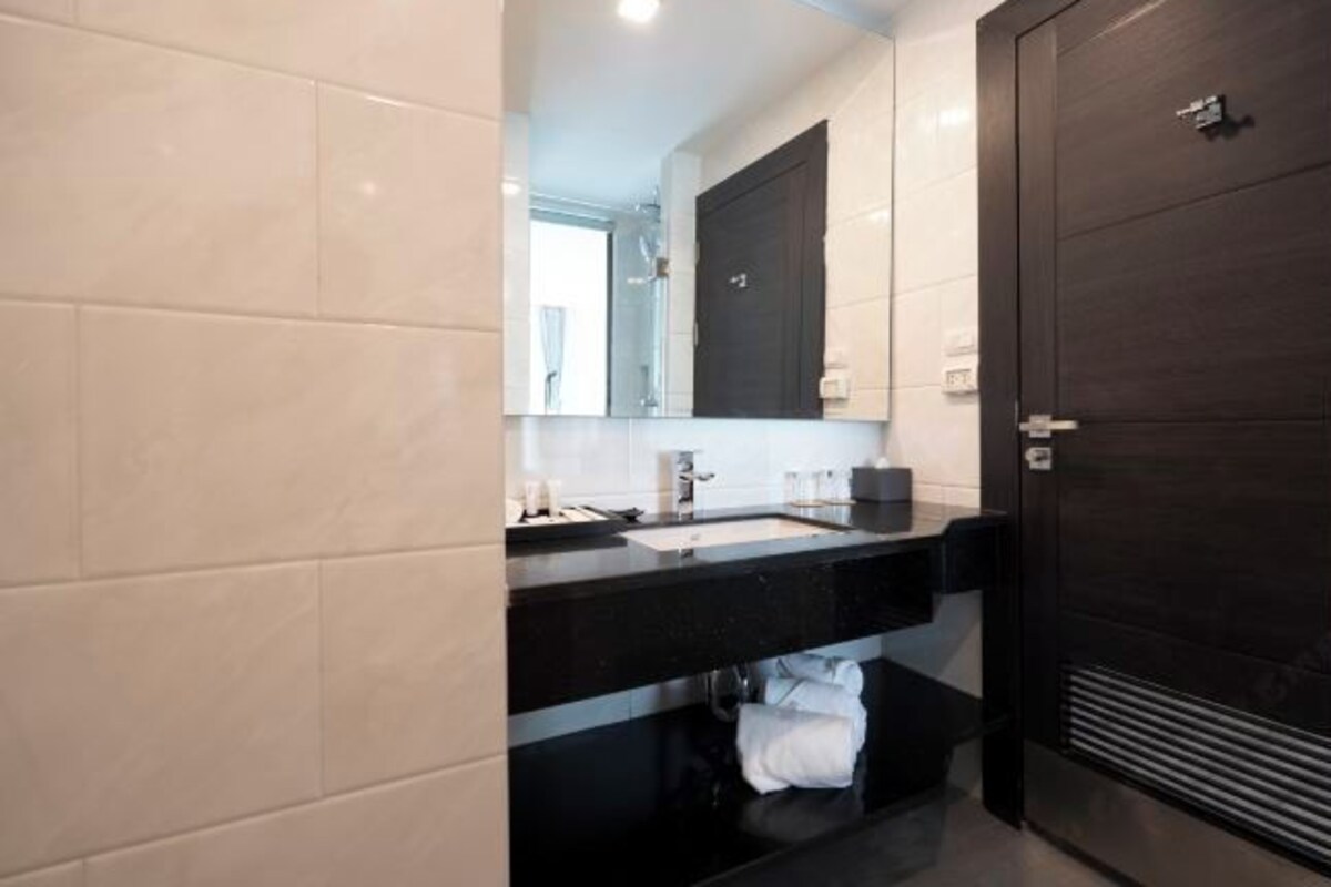 Un baño moderno con una puerta de madera oscura, una encimera negra y un lavabo blanco.