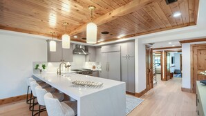 Une cuisine moderne dotée d’un îlot central, de tabourets de bar et de poutres en bois au plafond.