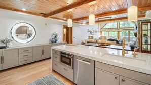 Une cuisine moderne dotée d’un îlot central, d’appareils électroménagers en acier inoxydable et d’un plafond en bois.