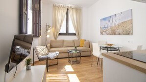 Ein modernes Wohnzimmer mit einer Couch, einem Esstisch, einem Stuhl und einem Fernseher.