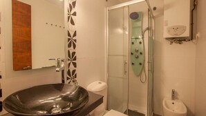Ein modernes Badezimmer mit einem großen schwarzen Waschbecken, einer Toilette, einer Duschkabine und einem Bidet.