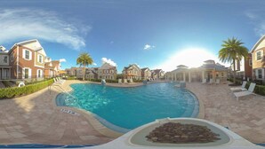 Une piscine entourée de maisons, un ciel dégagé et un soleil brillant.
