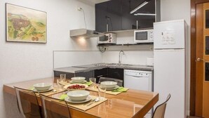 Una cocina compacta con una mesa de comedor para cuatro personas, microondas, estufa y refrigerador.