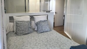 A modern bedroom with a large bed, two patterned pillows, a bedside table, and a mirror above the bed. - Realejo Paradise. Penthouse with terrace (Granada)