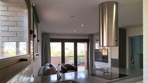 A modern kitchen with a stainless steel range hood, a built-in oven, and a large window overlooking a balcony. - Realejo Paradise. Penthouse with terrace (Granada)