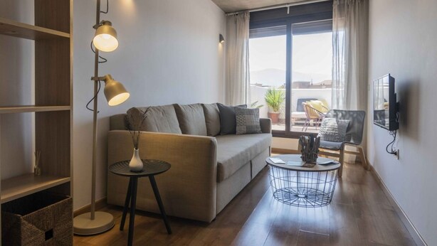 Un salon moderne avec un canapé, une table basse ronde, un lampadaire et un téléviseur fixé au mur.