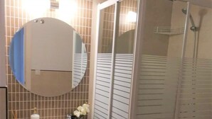 Une salle de bain avec un lavabo, un miroir et une douche.