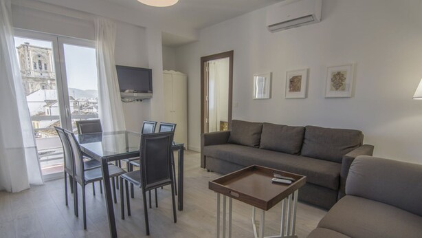 Ein modernes Wohnzimmer mit einer Couch, einem Couchtisch und einem Essbereich mit Stühlen und einem Glastisch.