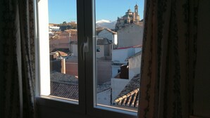 Ein Fenster mit Blick auf eine Stadtlandschaft, darunter Gebäude und ein Glockenturm.