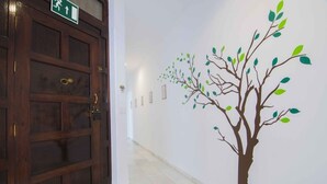 Un pasillo con una puerta de madera y un mural en la pared con un árbol.