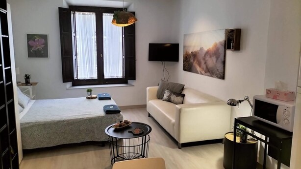 Un dormitorio moderno y bien iluminado con cama, mesita de noche y ventana con cortinas.