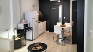 Cocina compacta con refrigerador, microondas y una pequeña mesa de comedor con sillas.