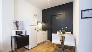 Una cocina compacta con microondas, refrigerador y un comedor con sillas y mesa.