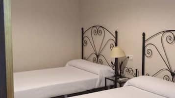 Una habitación con dos camas individuales, una mesita de noche con lámpara y una lámpara colgante.