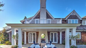 Una casa de dos pisos con un porche cubierto, una chimenea y un ventanal grande.