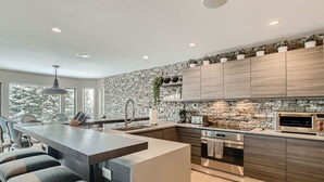 A modern kitchen with a stone backsplash, wooden cabinets, and a built-in oven. - 970-B Fairway Ct., Vail Golf Course Home - Hot Tub, Fire Pit,Gas Grill, Close to Lifts! (Vail)