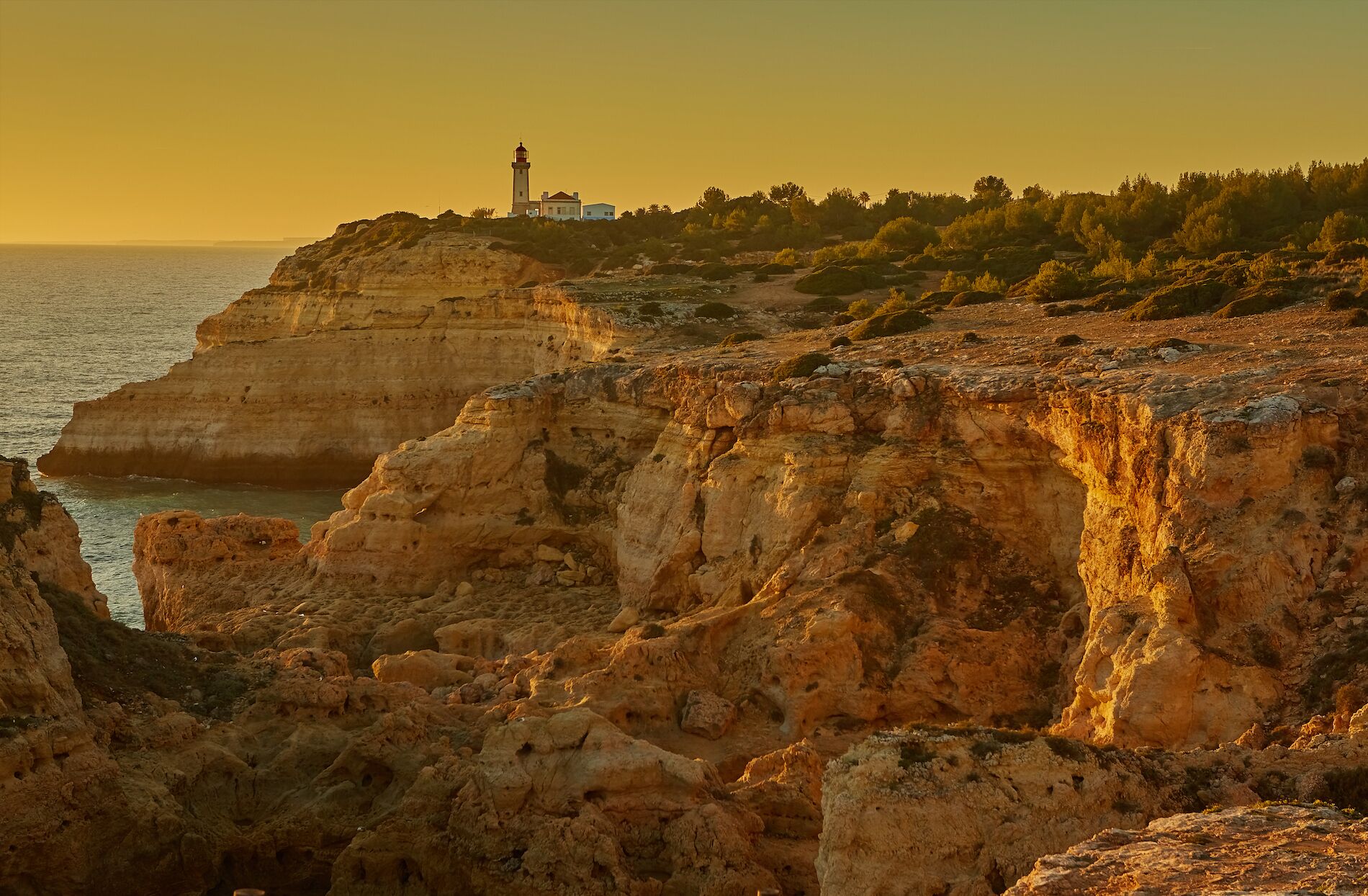 Un paisaje costero con un faro y acantilados rocosos.