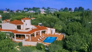 A large villa with a swimming pool, surrounded by lush greenery and other houses in the background. - Gorgeous villa ideally located with pool, ocean views, AirCo, great for families (Carvoeiro)