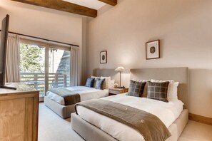 Une chambre d’hôtel avec deux lits, un bureau, une table de chevet et une fenêtre avec des rideaux.