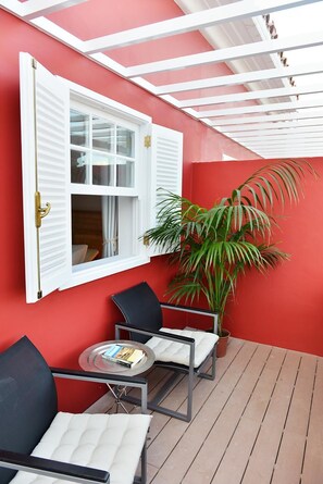 A red-walled room with a white window, two chairs, a small table, and a potted plant. - Casa Mozart Hotel Boutique (Las Palmas de Gran Canaria)