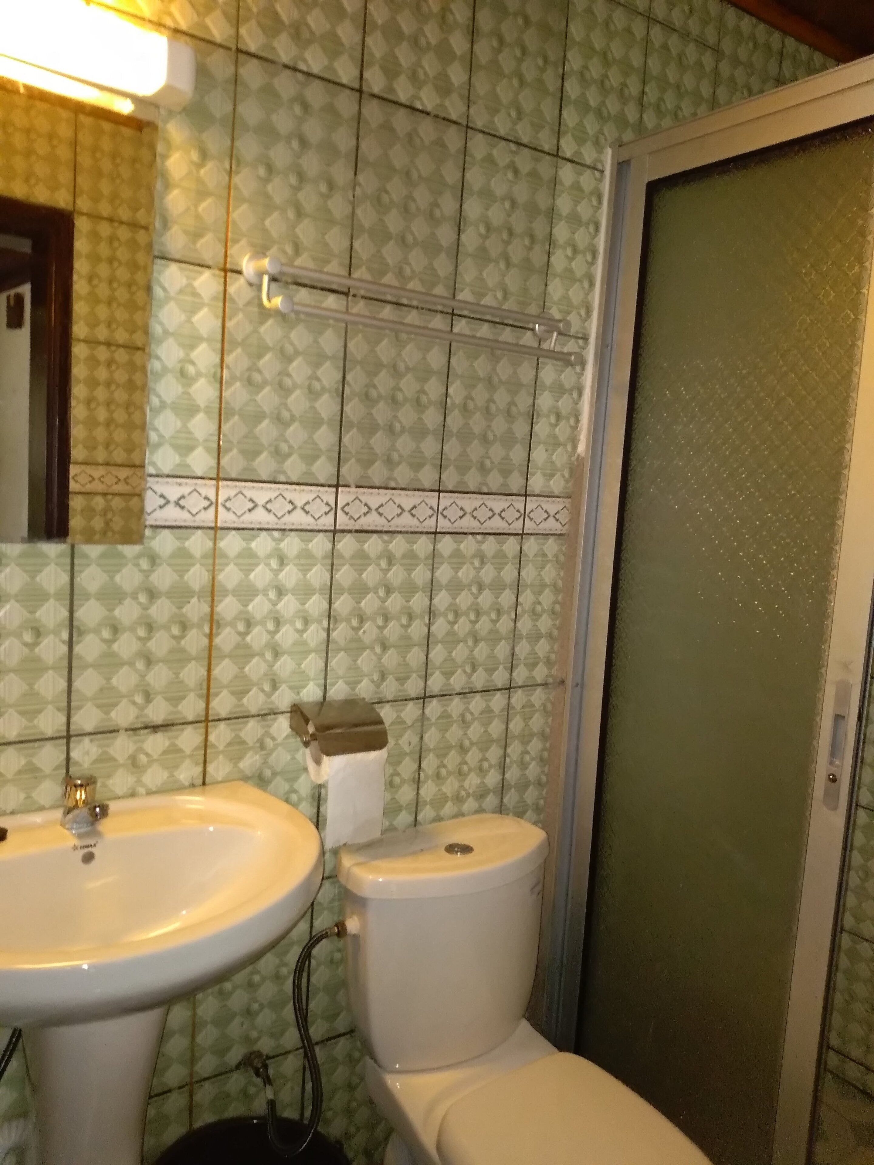 A bathroom with patterned tiles, a sink, a toilet, and a shower area.
