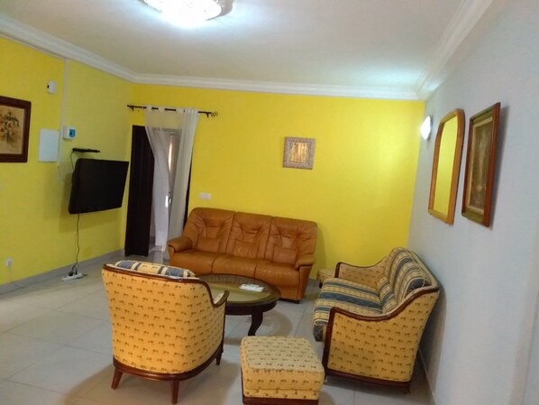 A living room with a sofa, two armchairs, a coffee table, and a TV.