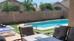 An outdoor patio with a pool, surrounded by a brick wall and greenery. - Relax in Home w/ Htd. Pool+Hot Tub,  Putting Green, Whirlpool Bath+Steam Shower (Queen Creek)