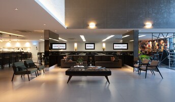 Um hall de hotel moderno com balcão de recepção, área de estar e um bar de café.