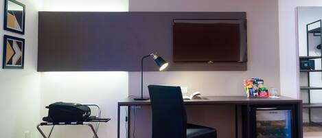 A compact workspace with a desk, chair, and a small refrigerator.