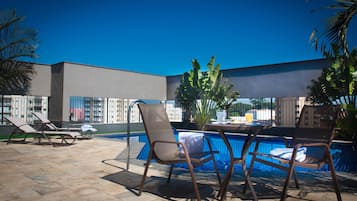 A poolside area with lounge chairs, a table, and a pool.