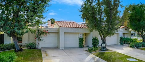 A residential house with a tiled roof, two garage doors, and a well-maintained lawn.