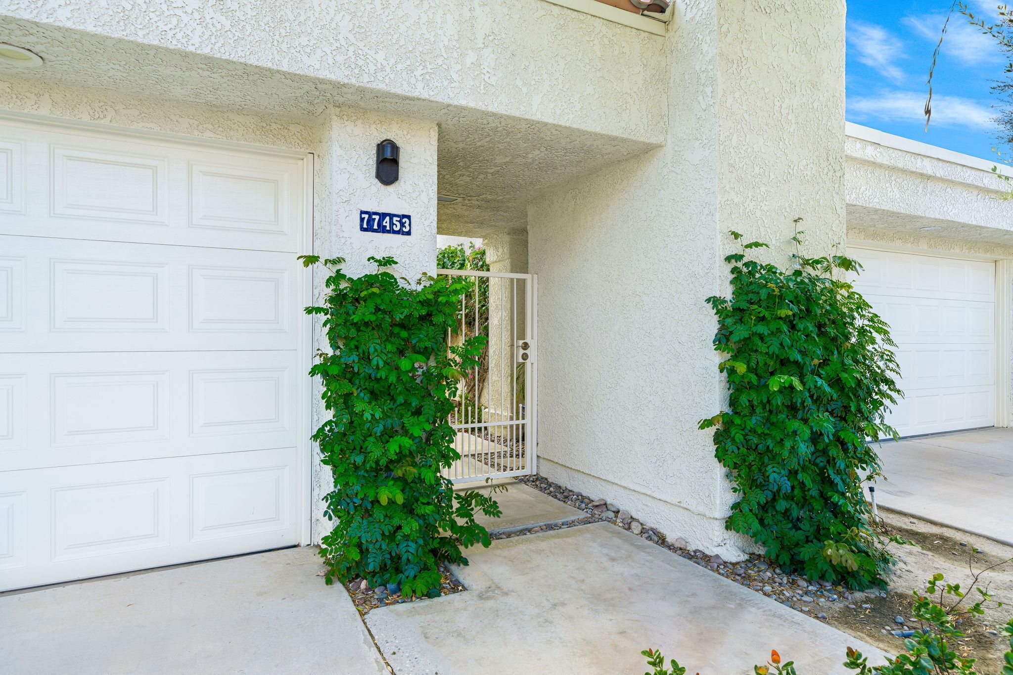 A residential garage with a white door, a mailbox, and a house number 77453.