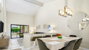 Een moderne eetruimte met een tafel voor vier personen, een kroonluchter en een grote spiegel aan de muur.