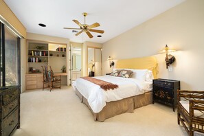 A bedroom with a bed, a ceiling fan, a bookshelf, a chair, and a nightstand.